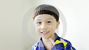 Portrait close up face of Cute Asian child in a blue shirt smiling and looking at the camera.
