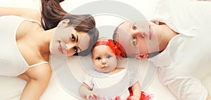 Portrait close-up happy family mother, father with baby lying on bed or carpet at home