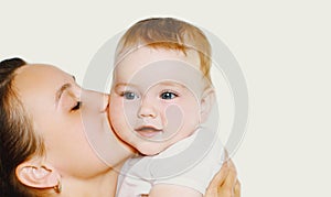 Portrait close up of happy mother kissing her cute baby over white background