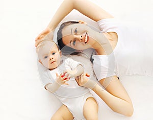 Portrait close-up happy smiling mother and baby lying on bed home