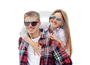 Portrait happy smiling young couple hugging together, man giving piggyback ride to woman wearing a sunglasses isolated