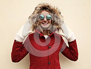 Portrait close up happy smiling young woman having fun wearing white mittens, red jacket with fur hood