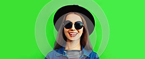 Portrait close up of happy smiling young woman wearing black round hat on green background