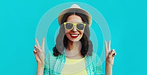 Portrait close up happy smiling young woman wearing a summer straw hat on a blue background