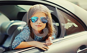 Portrait close up of little girl child sitting in car as passenger looking out of car window