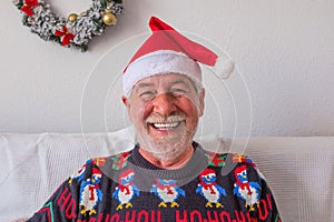 Portrait and close up of mature cheerful man smiling and looking at the camera laughing - senior wearing winter and christmas