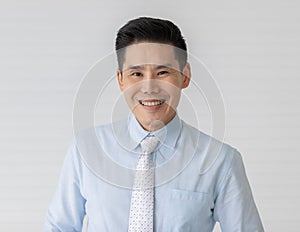Portrait close up shot of asian male model with short black hair wearing light blue shirt with white dot necktie stand smiling in