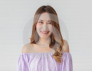 Portrait close up shot of young pretty asian female with long brown hair wearing light purple long sleeve shirt stand smiling with