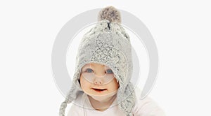 Portrait close up of smiling baby wearing winter knitted gray hat over a white background