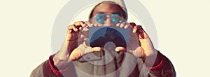 Portrait close up of stylish young african man stretching his hands for taking selfie by smartphone on white background