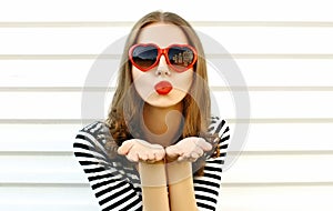 Portrait close-up woman blowing red lips sending sweet air kiss on white wall