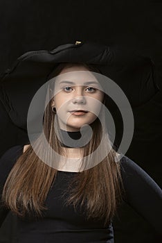 Portrait close up of young girl in black clothes and wide-brimmed hat. Young lady aristocrat