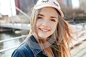 Portrait closeup beautiful young girl in city. Smiling girl in hat