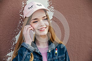 Portrait closeup beautiful young girl in city. Smiling girl in hat with smartphone