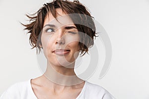 Portrait closeup of optimistic woman with short brown hair in basic t-shirt smiling and looking aside