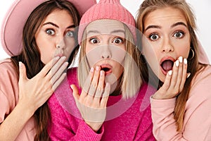 Portrait closeup of three amazed girls wondering and looking at camera