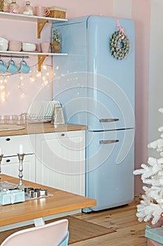 Portrait closeup view of interior of modern white kitchen with pink walls and blue decor on a Christmas New year eve