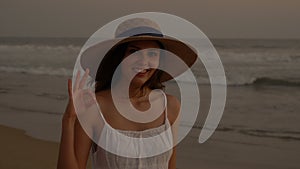 Portrait of a closeup of a young smiling girl in a hat on the shore of the Pacific Ocean. Woman in a white dress at