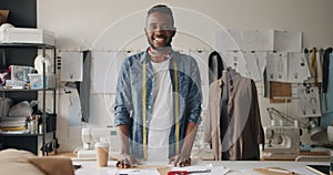 Portrait of clothes designer looking at camera standing in studio with dummy