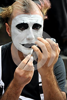 Portrait of a clown street artist in Florence, Italy putting makeup on before a street show