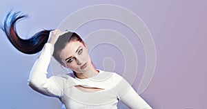 Portrait of cocky girl with long ponytail hair on studio background, young woman with rebellious character, fashion model