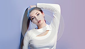 Portrait of cocky girl with long ponytail hair on studio background, young woman with rebellious character, fashion model