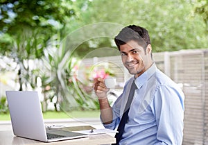 Portrait, coffee and laptop for businessman, smile and online work in cafe with notepad. Outside, internet and