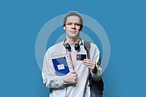 Portrait of college student guy with bank credit card, on blue background