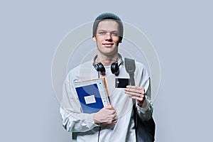 Portrait of college student guy with bank credit card, on gray background