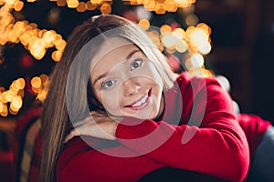 Portrait of comfy sitting at home young lady wearing red jumper folded hands hug herself sitting in divan isolated xmas