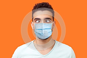Portrait of comic crazy positive brunette man with surgical medical mask looking cross-eyed, having fun with silly face expression