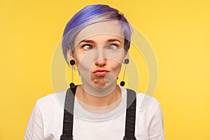 Portrait of comic hipster girl looking cross eyed, making silly awkward expression. yellow background, studio shot
