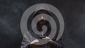 Portrait of computer hacker in hoodie. Obscured dark face. Data thief, internet fraud, darknet and cyber security .