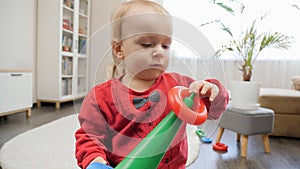 Portrait of concentrated baby boy assembling toy tower or pyramid. Concept of education and development