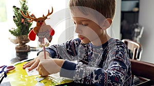 Portrait of concentrated boy in pajamas writing letter to Santa with his wishes on Christmas