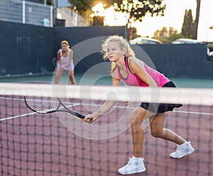 Portrait of concentrated energetic girl playing tennis, preparing to hit forehand to return ball close to net