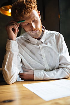 Portrait of concentrated readhead curly bearded man, reading pap