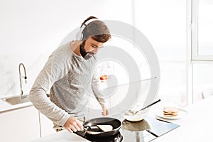 Portrait of a concentrated young man cooking pancakes