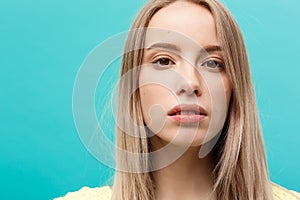 Portrait Concept: face of a beautiful young girl with a clean fresh face close up. over blue background.