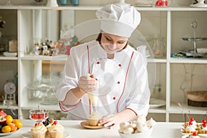 Portrait of confectioner topping a cupcake with cream