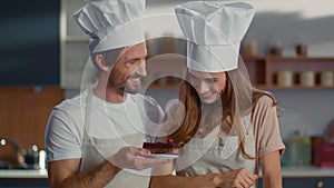 Portrait of confectioners decorating dessert with cherry on kitchen