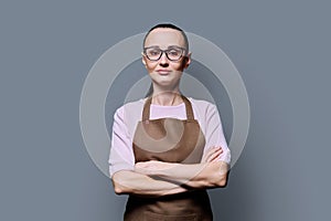 Portrait of confident 30s woman in apron on grey studio background