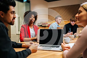 Portrait of confident African American business woman sitting at desk with laptop, looking at camera, during