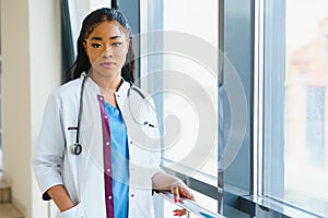 Portrait confident African American female doctor medical professional writing patient notes isolated on hospital clinic hallway