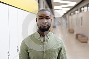 Portrait of confident african american young male teacher standing in school corridor