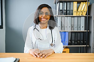 Portrait confident African female doctor medical professional writing patient notes isolated on hospital clinic hallway