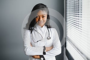 Portrait confident African female doctor medical professional writing patient notes isolated on hospital clinic hallway