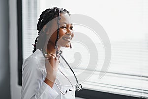 Portrait confident African female doctor medical professional writing patient notes isolated on hospital clinic hallway