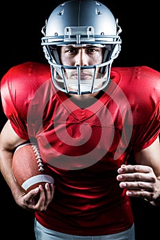 Portrait of confident American football player running while holding ball
