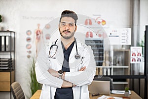 Portrait of confident Arabian male doctor posing at cabinet